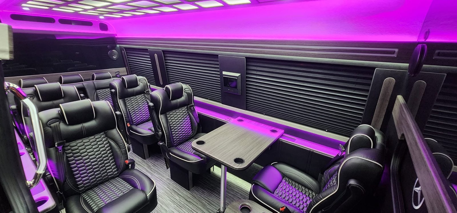 Executive Sprinter interior with leather seating, table and purple ambient lighting